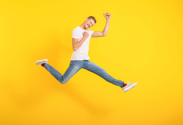Jumping man in stylish t-shirt on color background - Photo, image