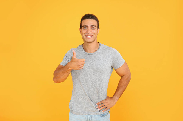 Handsome African-American man showing thumb-up on color background - Photo, Image