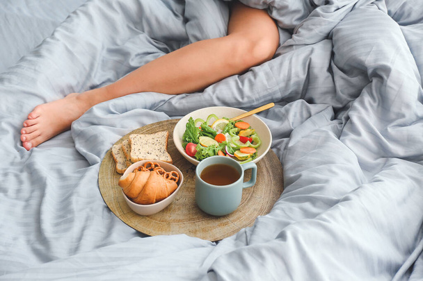 Vrouw met lekker ontbijt liggend op bed - Foto, afbeelding
