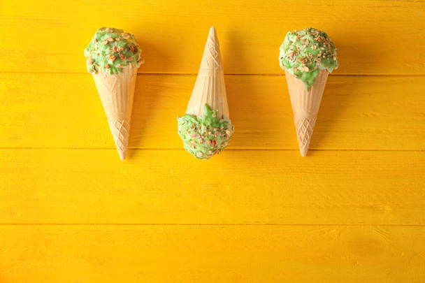 Oplatkové kornouty s chutnou pistáciovou zmrzlinou na dřevěném stole - Fotografie, Obrázek