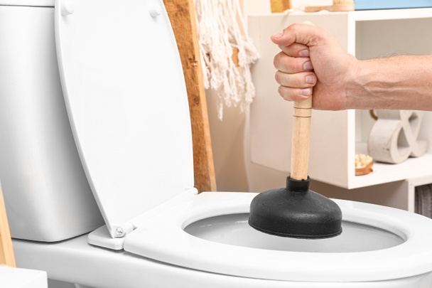 Man using plunger to unclog a toilet bowl - Photo, Image