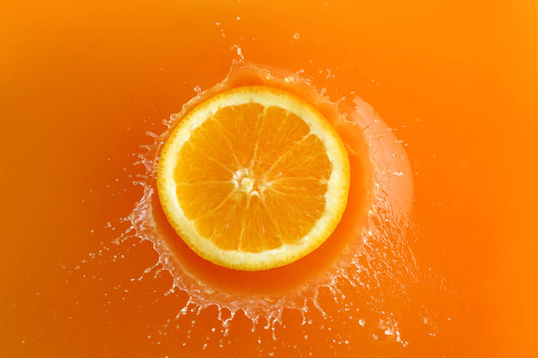Falling of orange piece into juice, top view - Foto, imagen