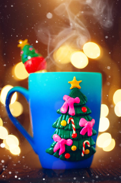 A Cup of hot cocoa in a Christmas mug on the background of Christmas garlands. Merry Christmas and happy New year. Selective focus. - Foto, imagen