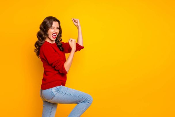 Photo of cheerful rejoicing overjoyed girlfriend wearing jeans denim isolated over yellow vivid color background with her hands up celebrating her victory - Valokuva, kuva
