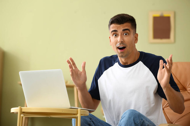 Shocked young man with laptop at home - Foto, imagen