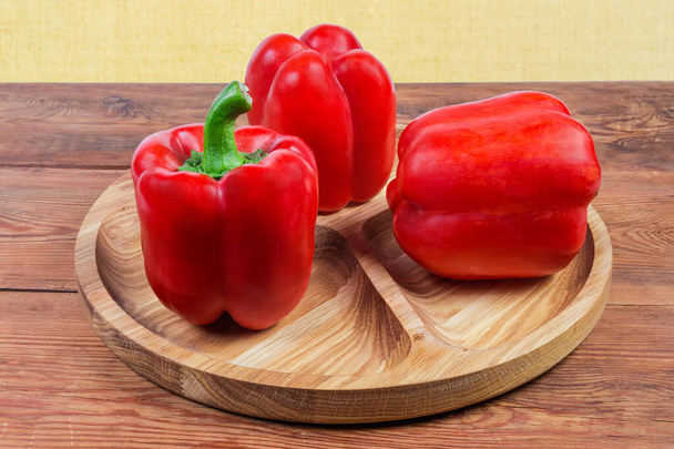 Красный перец на деревянном блюде на деревенском столе
 - Фото, изображение