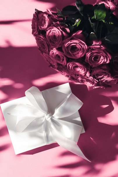 Πολυτελείς διακοπές μεταξωτό κουτί δώρου και μπουκέτο τριαντάφυλλα σε ροζ backgr - Φωτογραφία, εικόνα