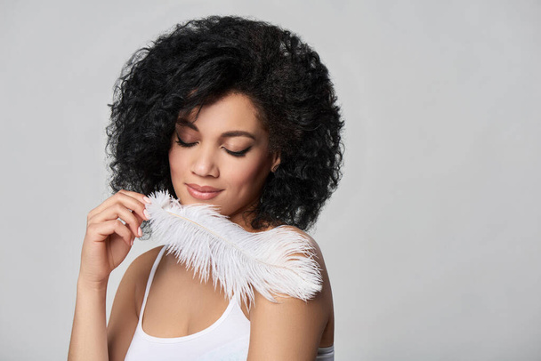 Beautiful mixed race woman holding white ostrich feather - Фото, изображение