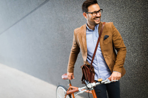 Young stylish businessman going to work by bike in the city - Zdjęcie, obraz