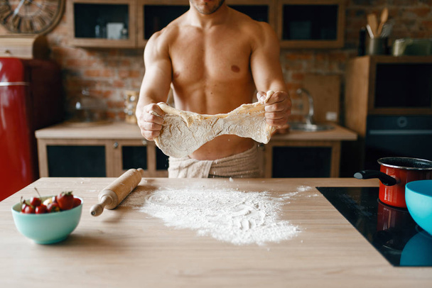 Спортсмен в нижній білизні готує на кухні. Голий чоловік готує сніданок вдома, приготування їжі без одягу
 - Фото, зображення