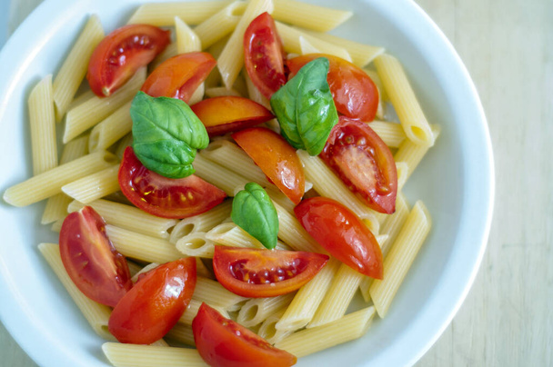 простая итальянская паста с оливковым маслом, свежими помидорами и базиликом
. - Фото, изображение