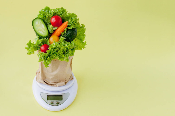 Fresh vegetables on scales on yellow background. Vegan and healt - Фото, изображение