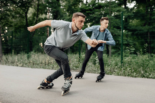 Görkorcsolyázás, két férfi korcsolyázó kezdődik gyorsasági verseny nyári parkban. Városi görkorcsolyázás, aktív extrém sport a szabadban, görkorcsolyázás - Fotó, kép