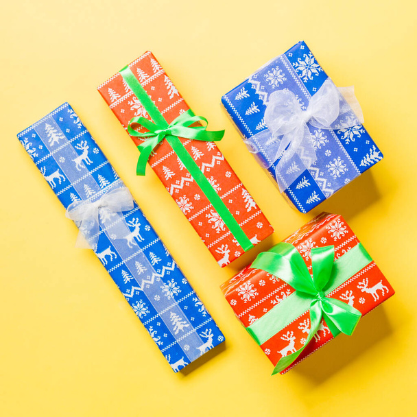 verpackte Weihnachten oder andere Feiertage handgemachtes Geschenk in Papier mit weißem und grünem Band auf gelbem Hintergrund. Geschenkbox, Geschenkdekoration auf farbigem Tisch, Draufsicht - Foto, Bild