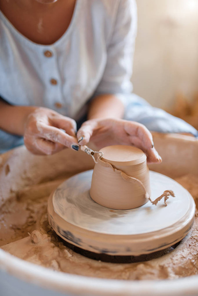 Ceramista femminile rimuove lo strato supplementare sulla pentola, ruota ceramica. Una donna che modella una ciotola. Arte ceramica fatta a mano, stoviglie in argilla
 - Foto, immagini