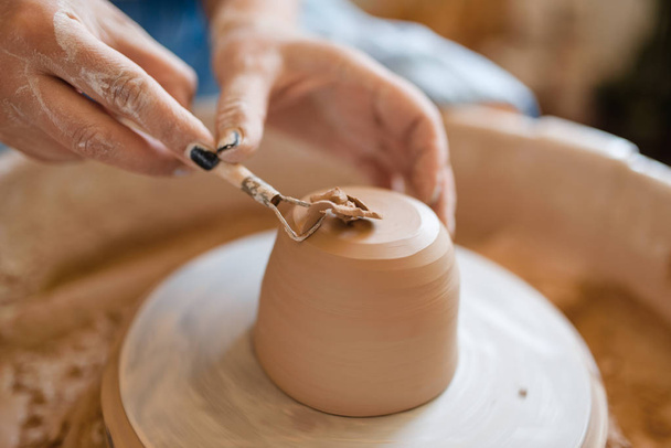 女性の陶芸家は、ポット、陶器ホイール上の余分な層を削除します。女性はボウルを成形.手作りの陶芸、粘土の食器 - 写真・画像