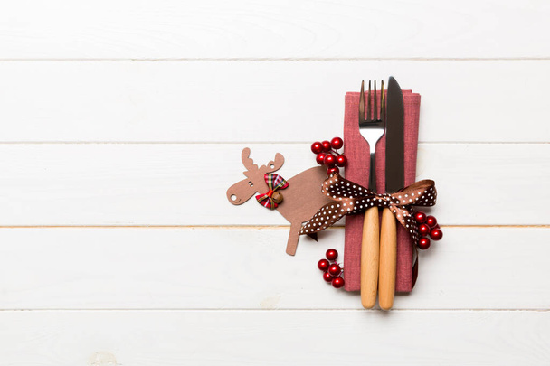 New year set of fork and knife on napkin. Top view of christmas decorations and reindeer on wooden background. Holiday family dinner concept with empty space for your design - Foto, Bild