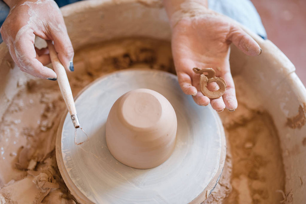 Mokrý hrnec na keramickém kole v dílně. Žena formuje mísu. Ručně vyráběné keramické umění, stolní nádobí z hlíny, tradiční koníček - Fotografie, Obrázek