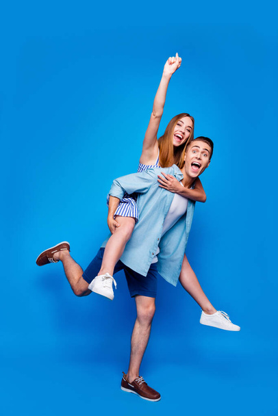 Vertical full length body size view of two nice attractive excited cheerful cheery glad positive people piggy-backing having fun isolated on bright vivid shine vibrant blue color background - Фото, изображение