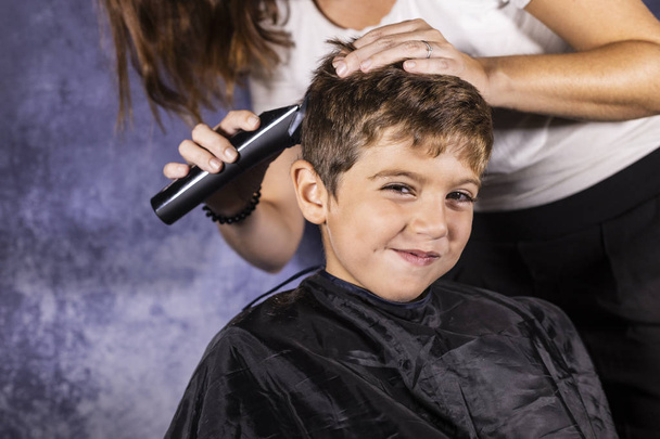 Niño pequeño cortándose el pelo con una máquina de cortar
 - Foto, Imagen