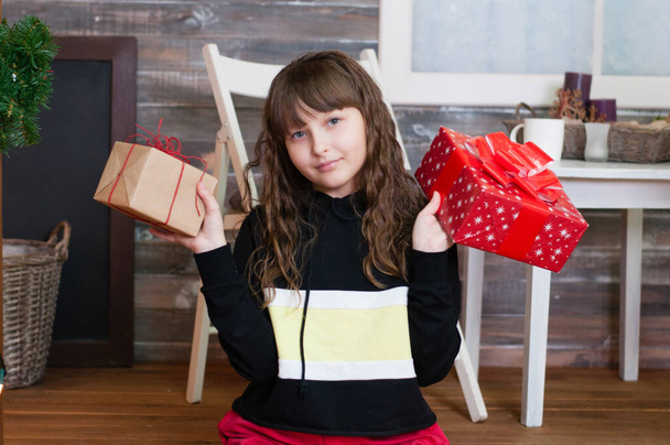 Счастливая улыбающаяся хорошенькая девочка с двумя подарками в руках. Подарки на день рождения или Рождество
 - Фото, изображение
