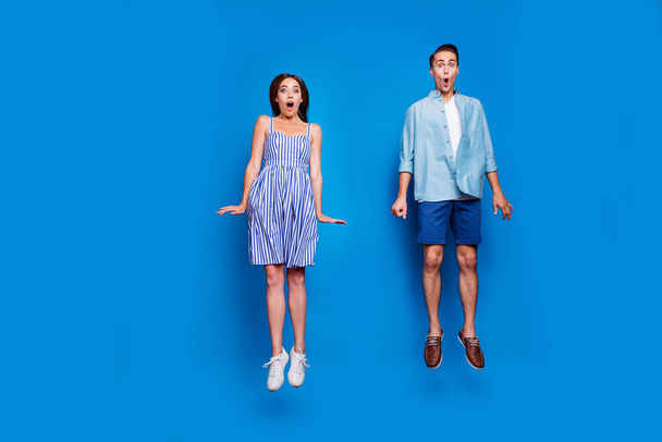 Full length body size view of two nice attractive funky comic childish cheerful cheery amazed people jumping having fun isolated on bright vivid shine vibrant blue color background - Photo, image