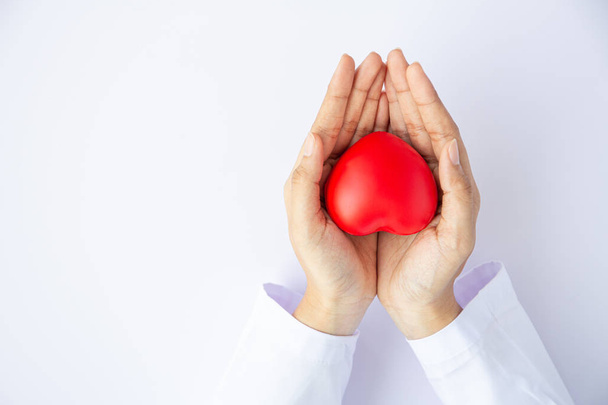 Nő orvos kéz gazdaság piros szív fehér háttér adományozás  - Fotó, kép