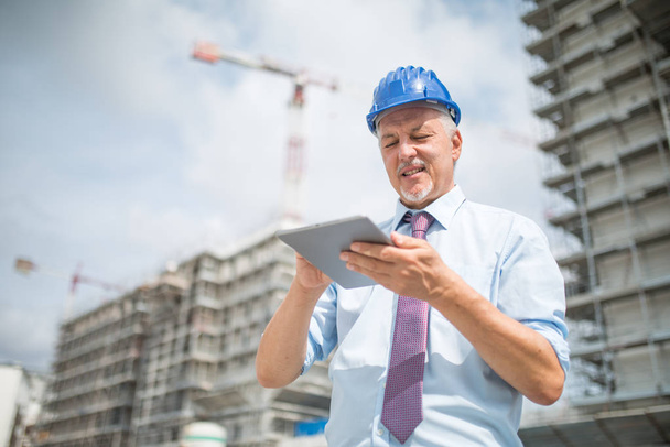 Site manager using his tablet in front of a construction site - Foto, Imagen