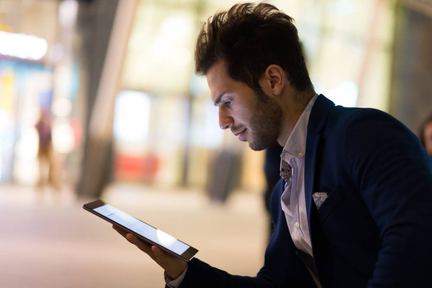 Young manager using a digital tablet outdoor in a modern city at night - Foto, Imagen