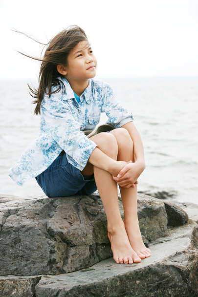 Niña de nueve años sentada junto al lago
 - Foto, imagen