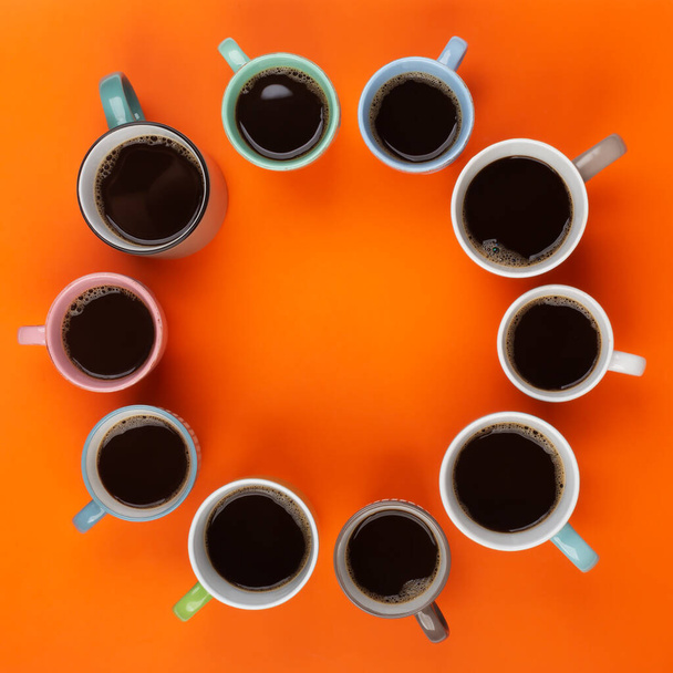 Coffee in the different cups on the bright orange background. Flatlay, cheerful day concept with copy space - Photo, Image