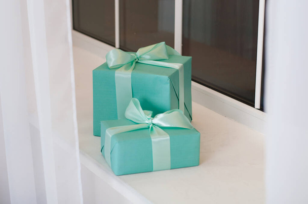 Christmas, New Year festive background of boxes with gifts in turquoise colors on the white windowsill - Photo, Image