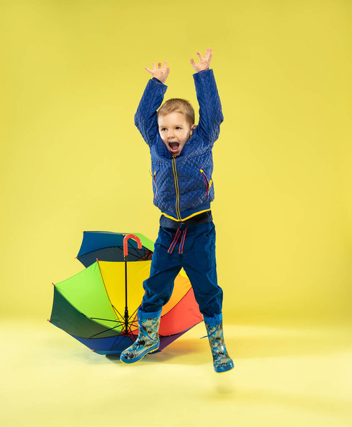 A full length portrait of a bright fashionable kid in a raincoat - Foto, afbeelding