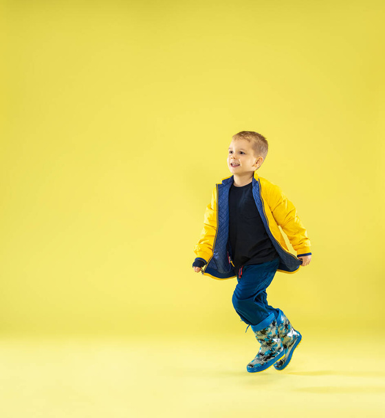 A full length portrait of a bright fashionable boy in a raincoat - Foto, afbeelding