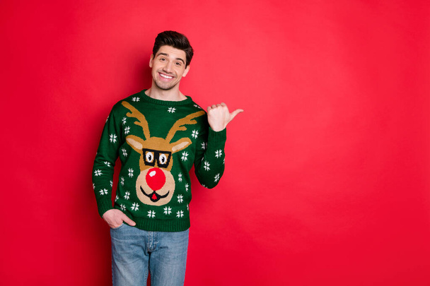 Portrait of funny festive brown hair in deer style stylish sweater point his thumb at copy space recommend winter shopping season sales isolated over red color background - Photo, Image