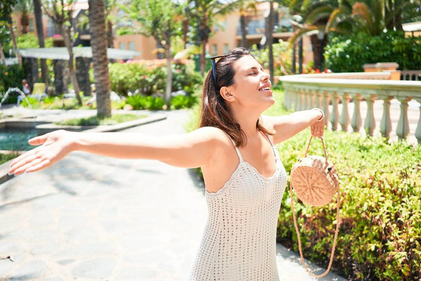 junge schöne Frau lächelt glücklich und positiv mit offenen Armen beim Sonnenbaden und dem Gefühl der Freiheit rund um den Urlaubsort - Foto, Bild