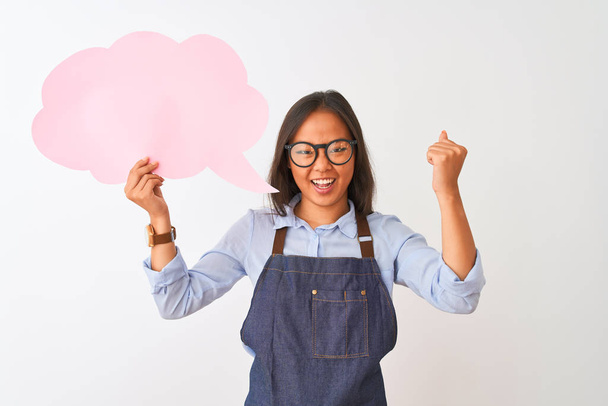 Chinese woman wearing glasses apron holding speech bubble over isolated white background annoyed and frustrated shouting with anger, crazy and yelling with raised hand, anger concept - Photo, Image
