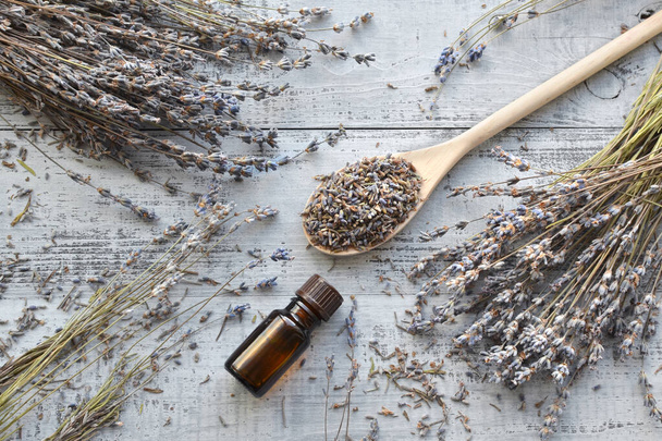 Dry lavender flowers bunches, essential lavender oil, lavender buds in big wooden spoon over wooden background. Flatlay - 写真・画像