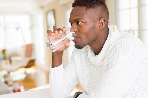 新鮮な水のガラスを飲む若いアフリカ系アメリカ人 - 写真・画像