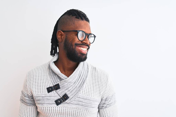 Homem afro-americano vestindo camisola cinza e óculos sobre fundo branco isolado olhando para o lado com sorriso no rosto, expressão natural. Rindo confiante
. - Foto, Imagem