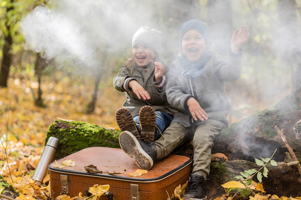 Dzieci bawiące się w jesiennym lesie pełnym żółtych liści z winem - Zdjęcie, obraz