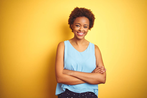 Bella donna afroamericana che indossa camicia elegante su sfondo giallo isolato volto felice sorridente con le braccia incrociate guardando la fotocamera. Persona positiva
. - Foto, immagini