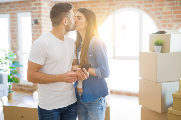 junges Paar zieht in ein neues Haus und freut sich mit Smartphone über neue Wohnung - Foto, Bild