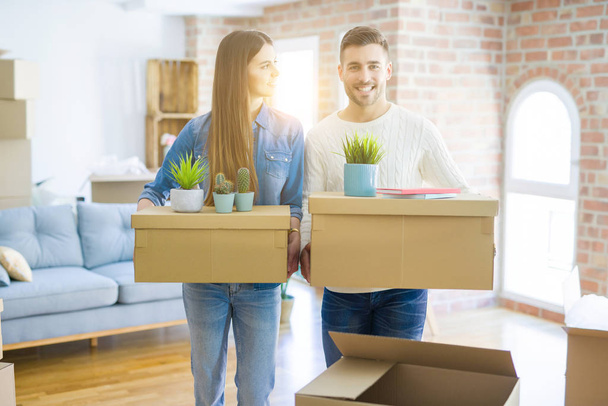 Young couple moving to a new home, smiling happy holding cardboard boxes at new apartment - Photo, Image