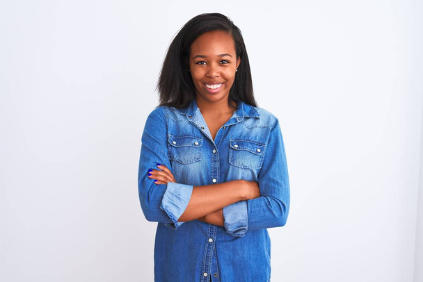 Красива молода афроамериканка, одягнена в джинсову куртку над ізольованим фоном, радісно посміхається з перехрещених рук, дивлячись на камеру. Позитивна людина. - Фото, зображення