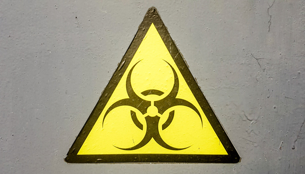 Σήμα βιολογικού κινδύνου σύμβολο προειδοποίηση βιολογικού κινδύνου, μαύρο κίτρινο τρίγωνο σήμανση μακροεντολή σε γκρι μεταλλικό τοίχο - Φωτογραφία, εικόνα