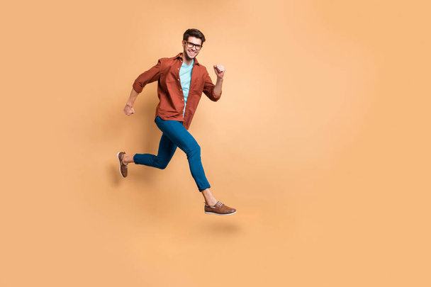 Full length body size view of nice attractive cheerful cheery strong sportive successful guy leader jumping in air running fast hurry-up meeting appointment isolated over beige color pastel background - Фото, изображение