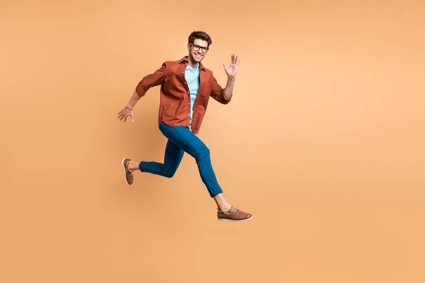 Full length body size view of his he nice attractive cheerful cheery glad active successful guy leader jumping in air running fast hurry-up meeting isolated over beige color pastel background - Foto, afbeelding