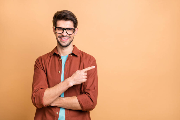 Close-up portrait of his he nice attractive cheerful cheery glad successful content brunet guy pointing forefinger aside advice advert solution isolated over beige color pastel background - Foto, immagini