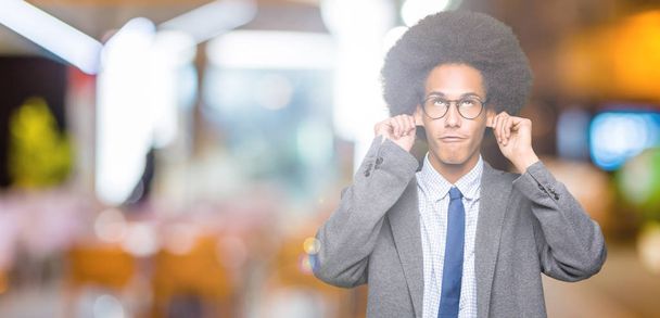 Молодих афро-американських бізнес людина з афро волосся в окулярах посміхаючись потягнувши вуха з пальцями, смішні жест. Прослуховування проблема - Фото, зображення
